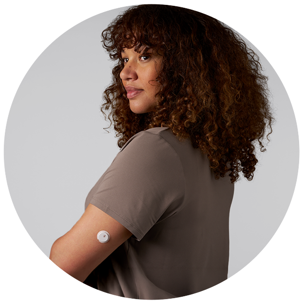 A woman wearing a continuous glucose monitor on the upper arm
