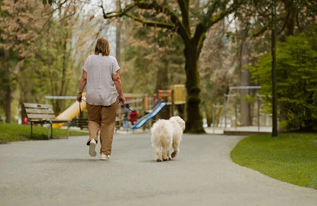 Mujer paseando por el parque con su perro, disfrutando del movimiento y del entorno