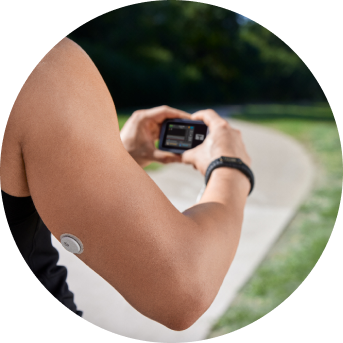 Woman looking at a t:slim X2™ insulin pump while wearing a FreeStyle Libre 3 Plus sensor