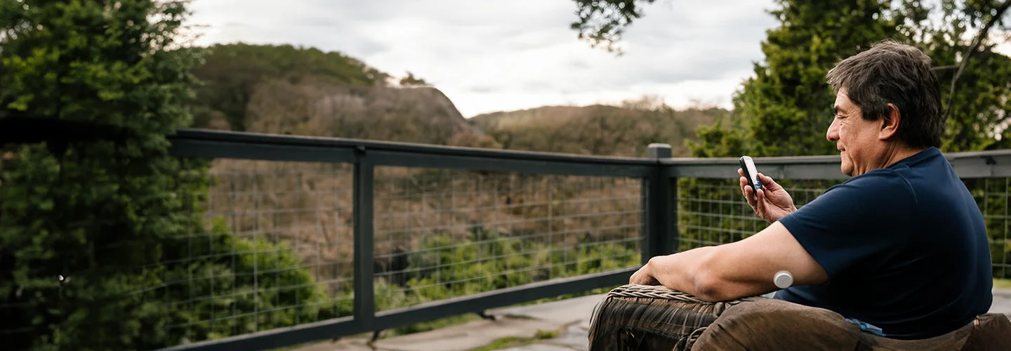 Homem com sensor no braço está mexendo no leitor FreeStyle Libre