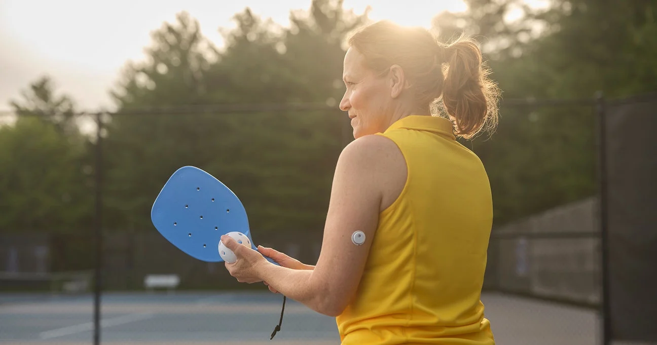 Person spiller pickleball som en illustration af en aktiv livsstil med en glukosesensor