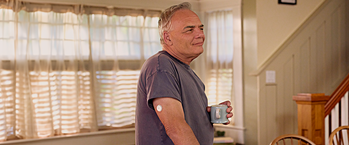 Žena v športovom oblečení so senzorom FreeStyle Libre 2 stojaca na ceste v parku.