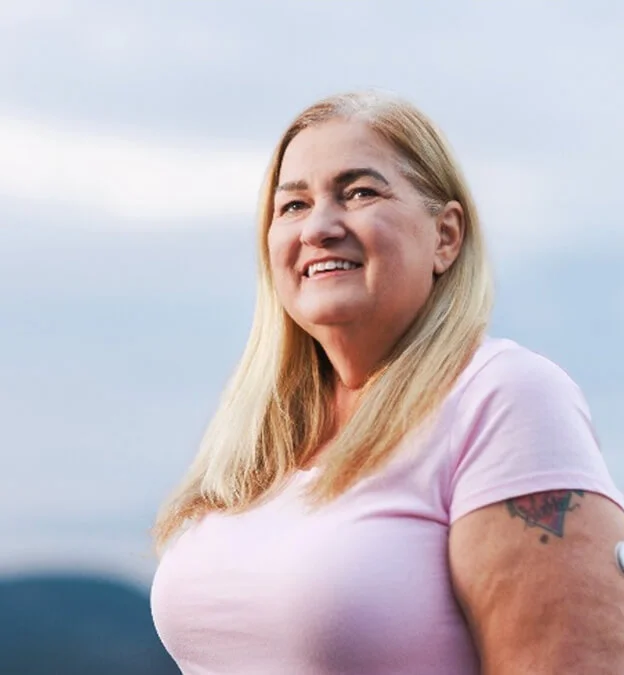 Mujer con una sonrisa suave y expresión serena al aire libre, simbolizando equilibrio y calidad de vida