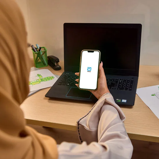 A woman holding her phone and checking her glucose data on the phone.