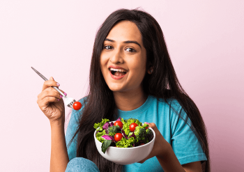 Woman smiling and eating a bowl of salad