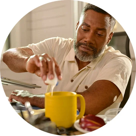 Person pouring creamer into a yellow mug at a table.