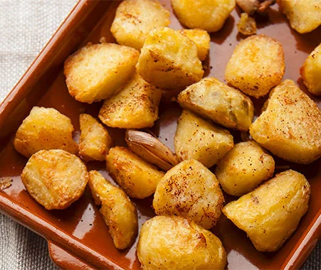 Roasted potato chunks seasoned with spices and served in a rustic baking dish.