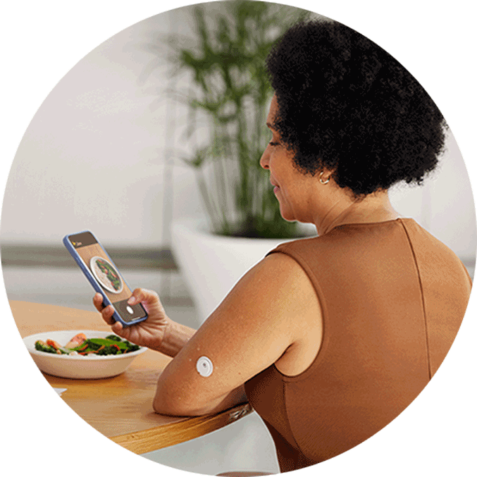Woman taking a photo of her meal while wearing a FreeStyle Libre 3 Plus sensor