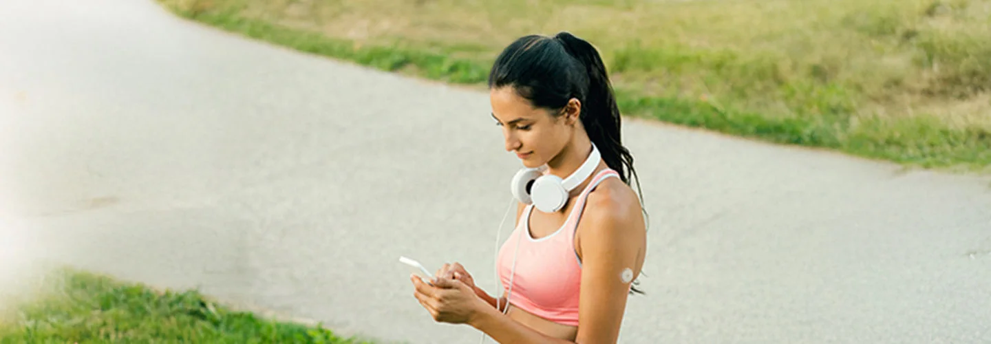 Mulher no parque com fone de ouvidos está mexendo no celular