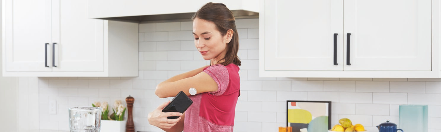 Uma mulher em uma cozinha conectando seu smartphone ao seu sensor.
