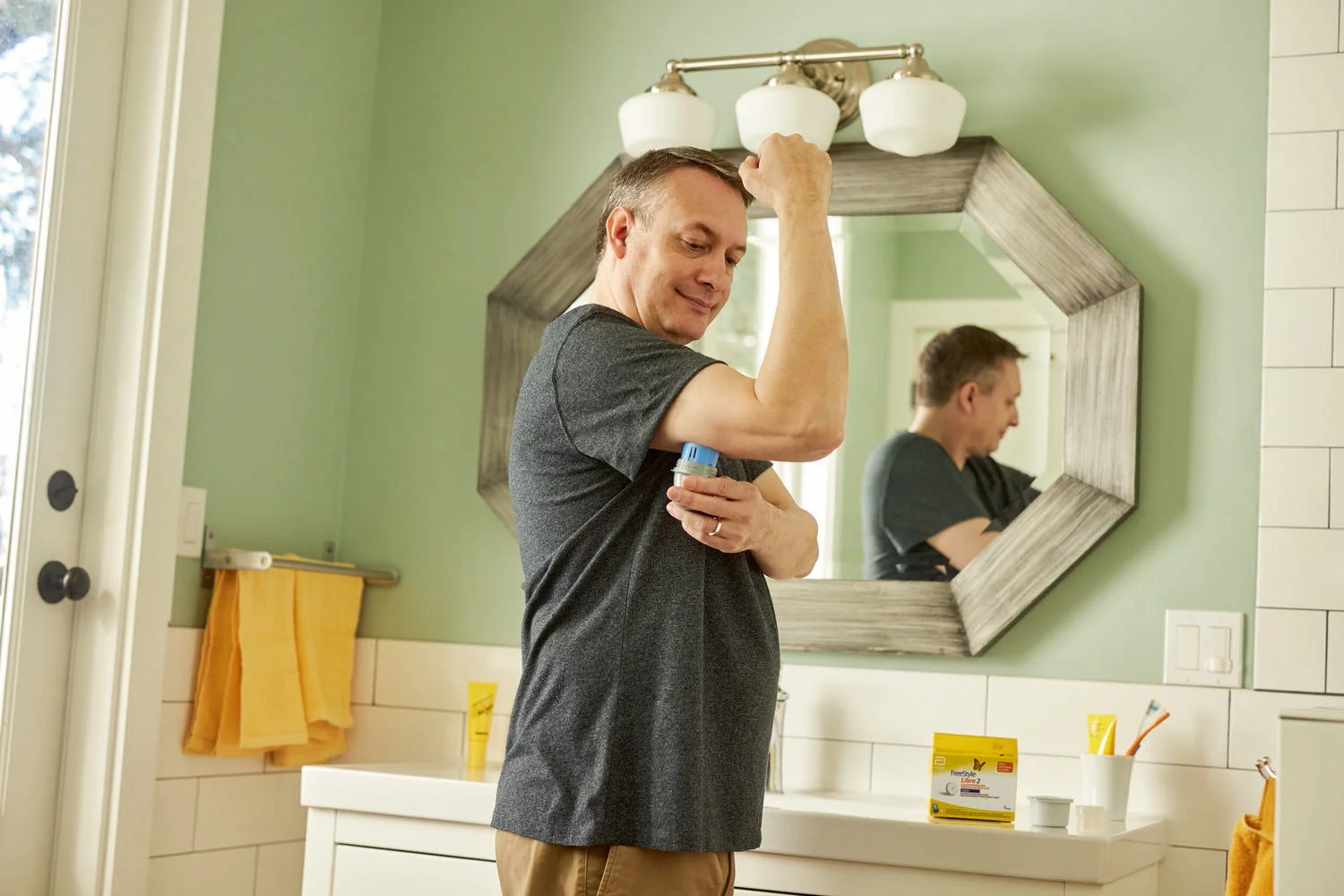 A man applying a FreeStyle Libre 2 sensor on his arm
