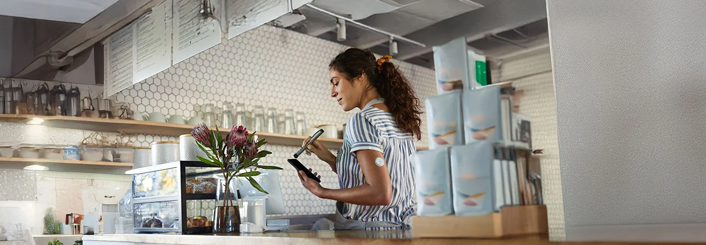 woman wearing a FreeStyle Libre sensor, examining glucose levels on an insulin pump.