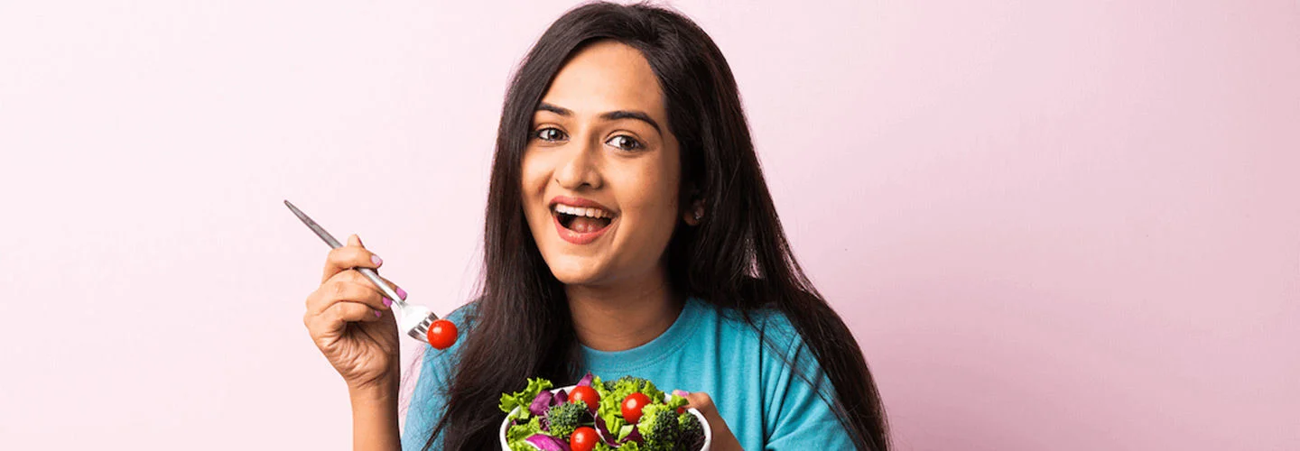 Woman smiling and eating a bowl of salad