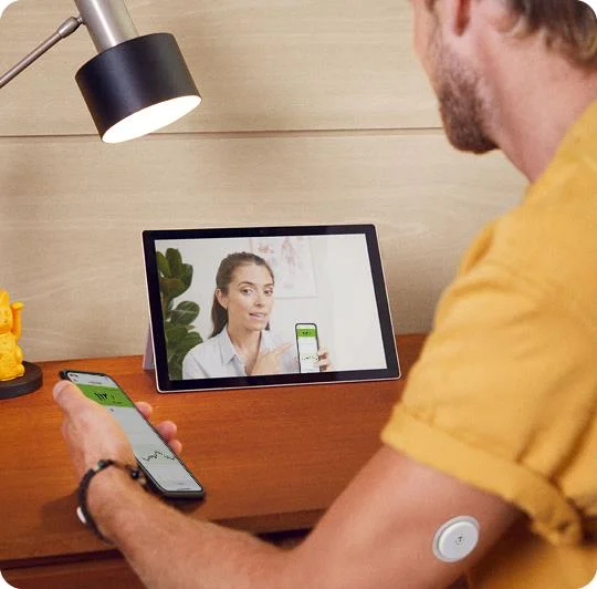 A man wearing a FreeStyle Libre sensor while speaking with his doctor on a tablet.
