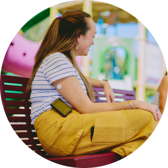 Woman sitting on a bench wearing a FreeStyle Libre 3 sensor and BetaBionics insulin pump