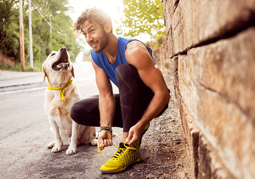 Muž so senzorom FreeStyle Libre 2 sedí na schodoch a po tréningu kontroluje aplikáciu FreeStyle LibreLink.