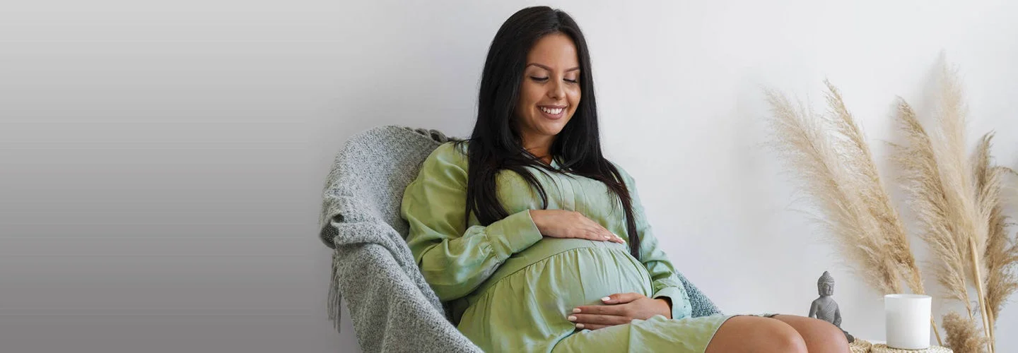 Pregnant woman rubbing her belly while sitting on a chair