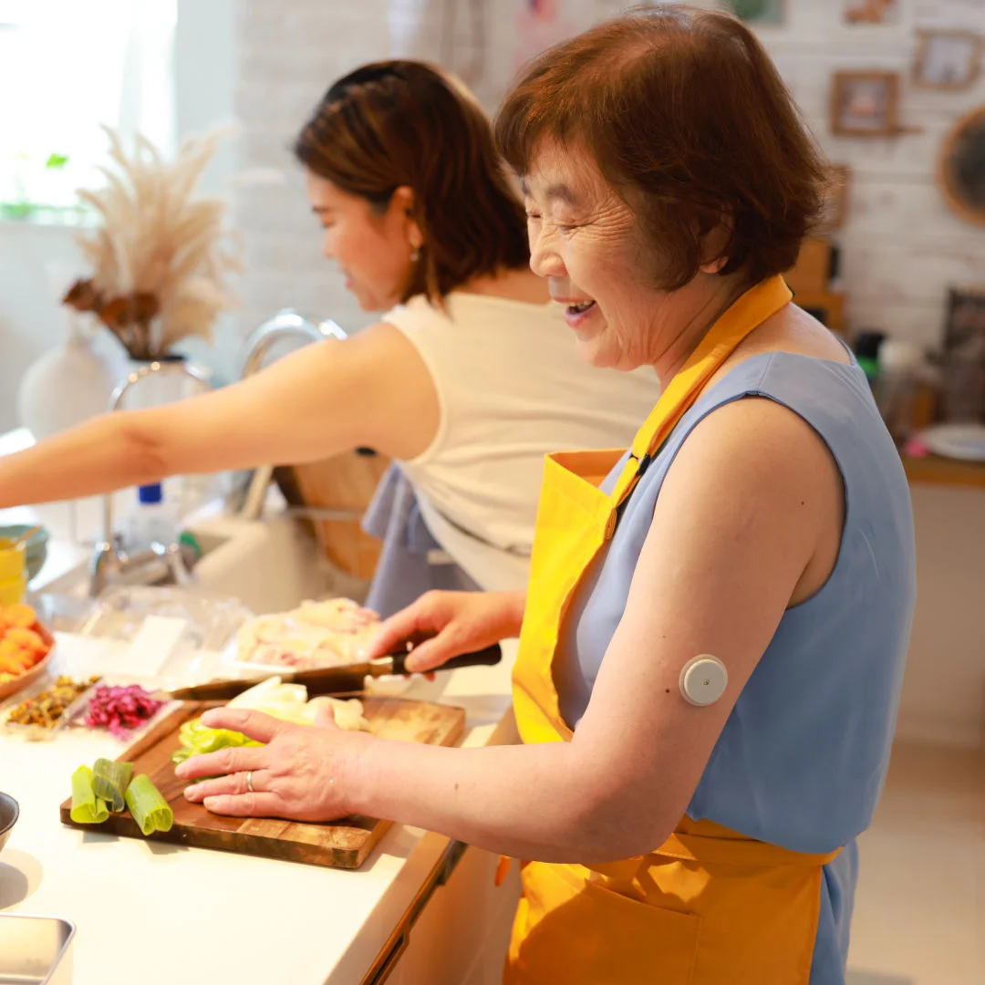 A woman wearing a FreeStyle Libre sensor prepping meal in the kitchen