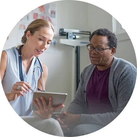 Healthcare provider reviews information on a tablet with a patient during a clinic consultation.
