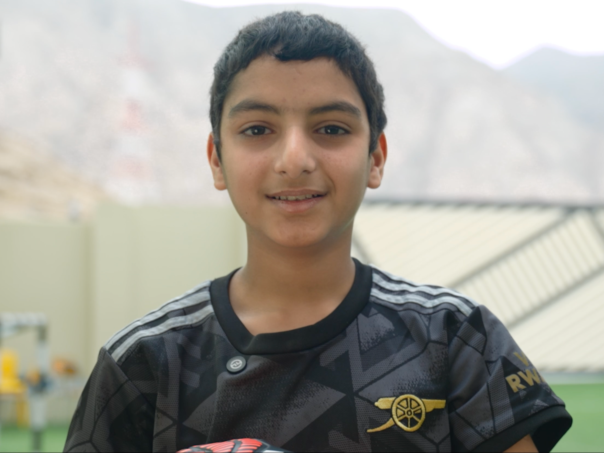 A woman wearing a sensor and holding her child in front of a fountain.