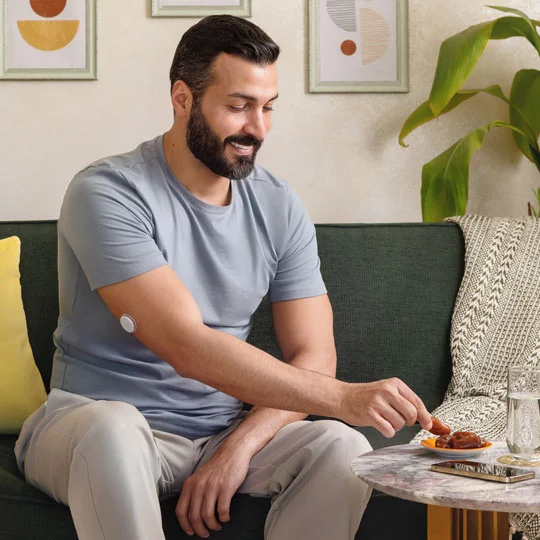 A man wearing a FreeStyle Libre sensor sitting in living room.