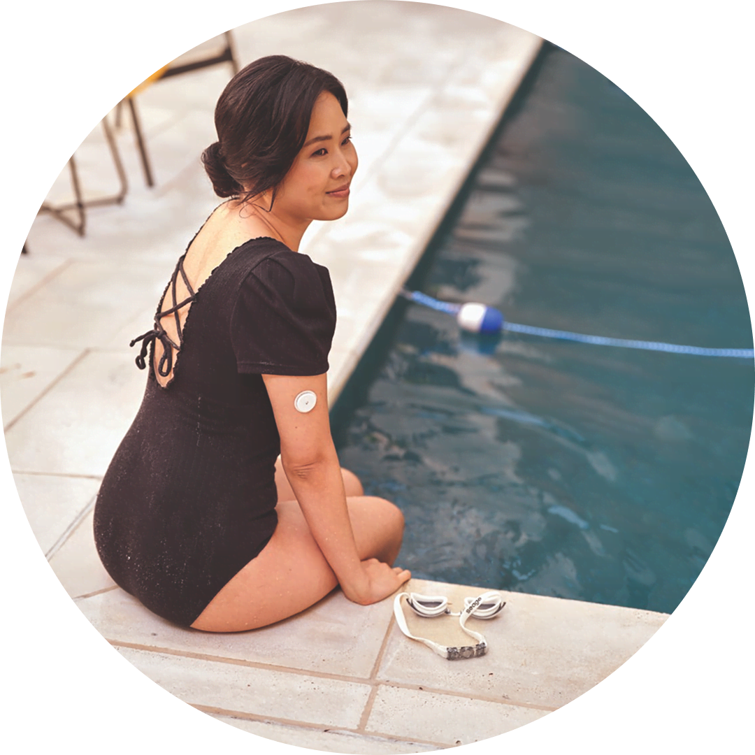 A woman wearing a FreeStyle Libre sensor relaxes by the pool.