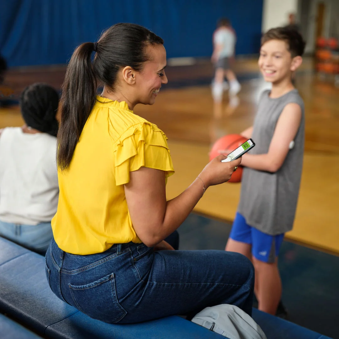 Mulher em quadra esportiva mexendo no aplicativo LibreLink