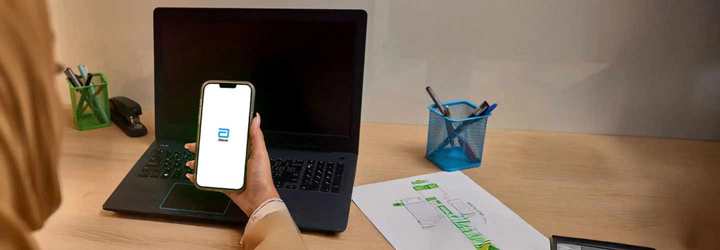   A woman looking at the Abbott  app splash screen on her phone.