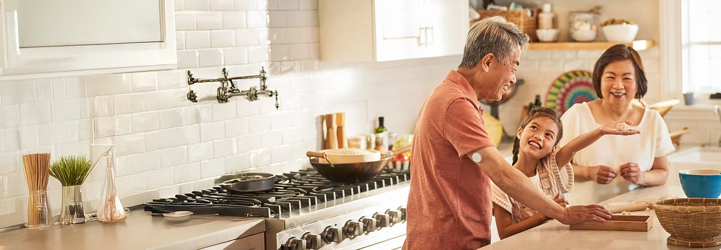 一位年長男士擁抱著小女孩，兩人臉上笑容洋溢，男士右上手臂配戴 FreeStyle Libre2 傳感器。在他們旁邊，一位年長女士微笑注視這個情景，散發出慈愛的氛圍。