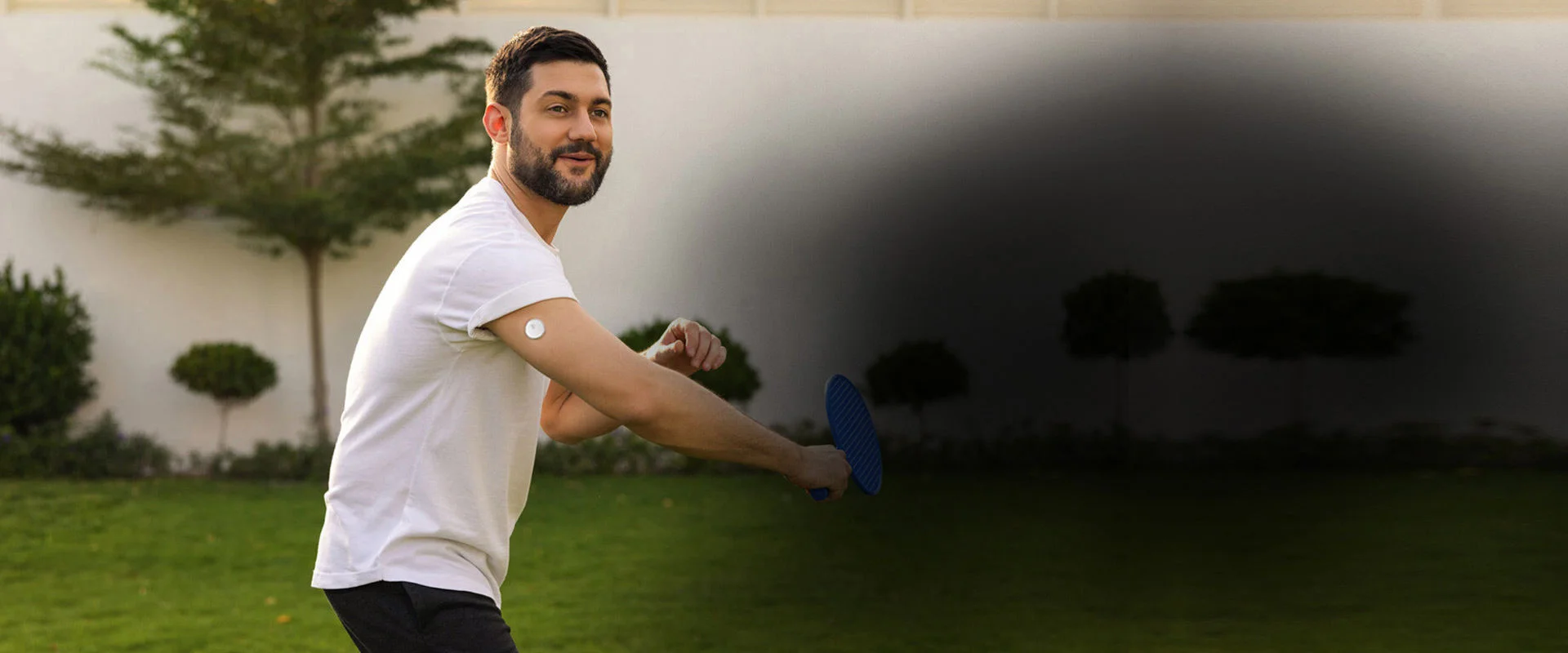A man playing horseshoes and wearing a FreeStyle Libre sensor.
