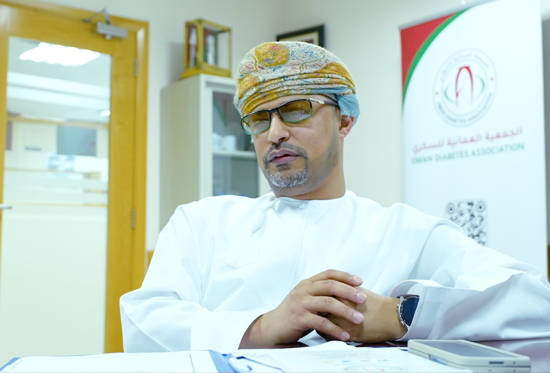 A woman wearing a sensor and holding her child in front of a fountain.