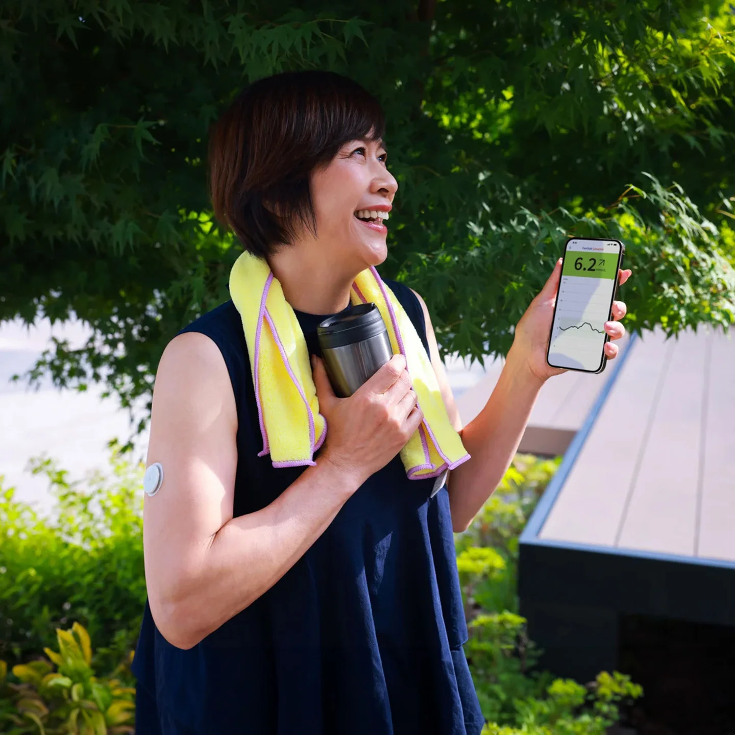 Woman wearing FreeStyle Libre sensor checks glucose level on smartphone .