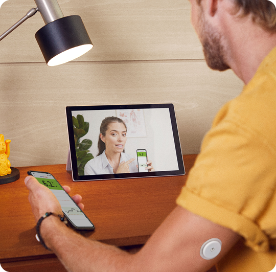 A man wearing a FreeStyle Libre sensor while speaking with his doctor on a tablet.