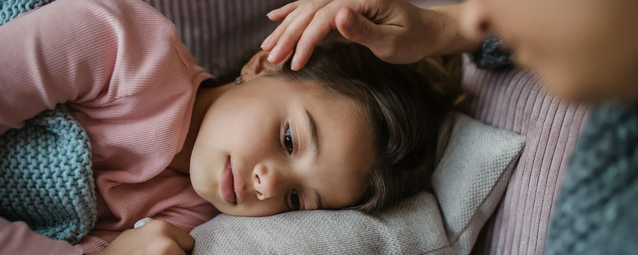mother stroking the head of sick child lying down.