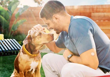 Homem com cachorro usando um sensor FreeStyle Libre