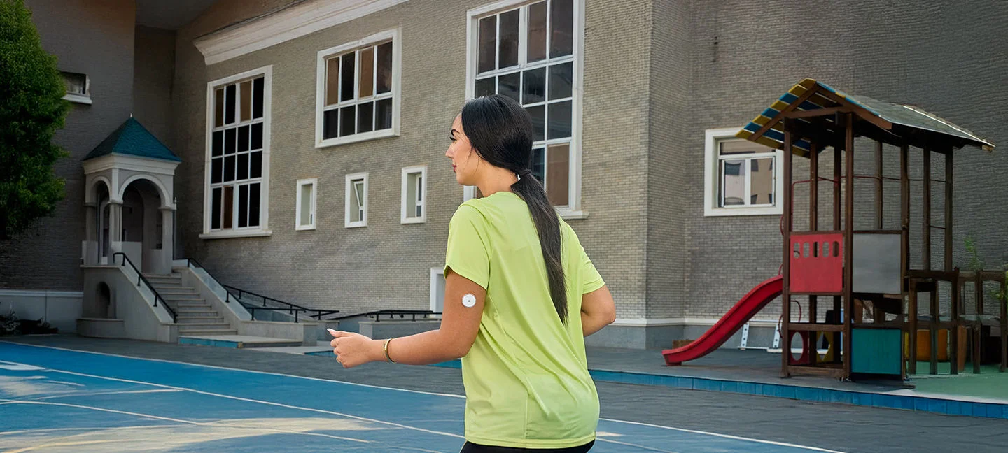 A woman running while wearing a FreeStyle Libre sensor.