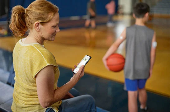 Woman checking her child’s FreeStyle Libre 3 Plus sensor