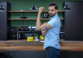 A man applying his FreeStyle Libre sensor on the upper back of his left arm.