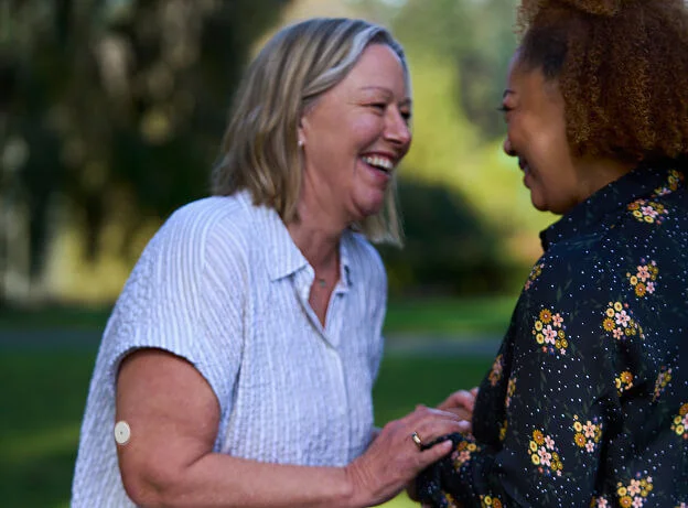 Mujeres riendo juntas en un parque, representando amistad, apoyo y bienestar emocional 