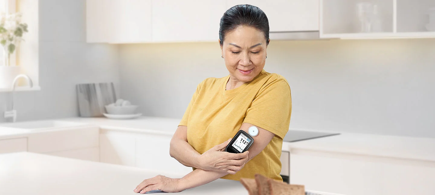A woman wearing a Freestyle Libre sensor and scanning the data with a reader