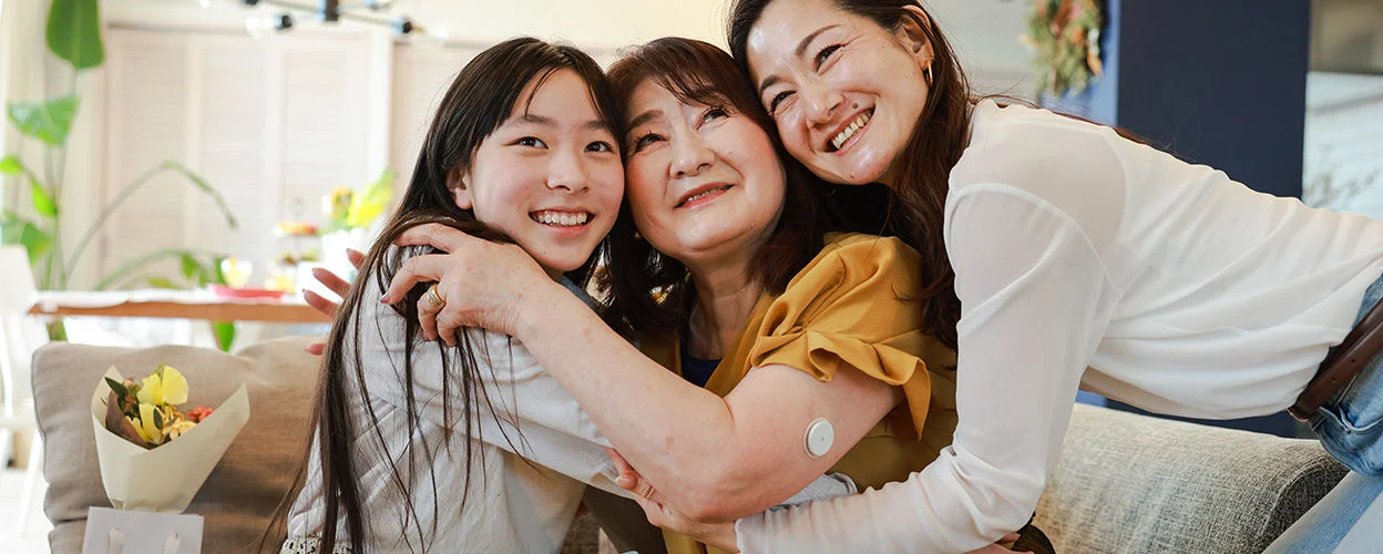 A woman wearing sensor with her family group hug and smiling.