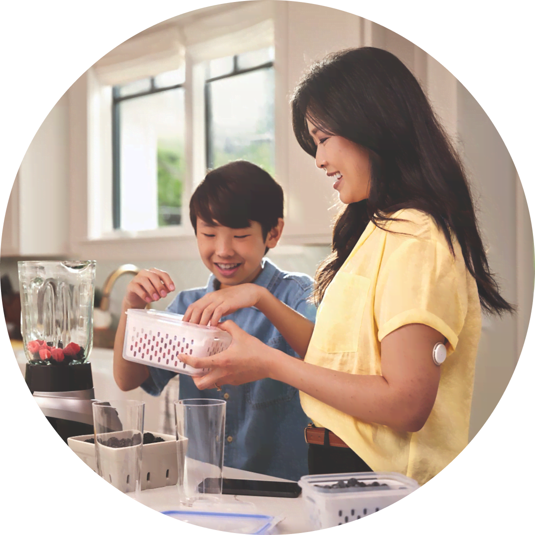 A woman wearing a FreeStyle Libre sensor prepares fruit for smoothies with her son.
