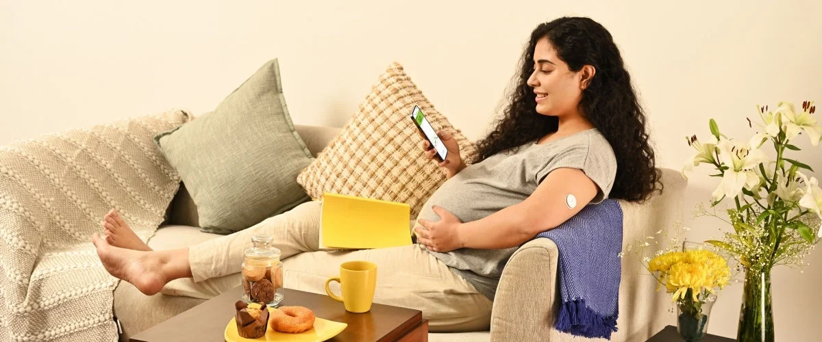 A woman wearing a sensor showing her glucose data on her phone with her husband.