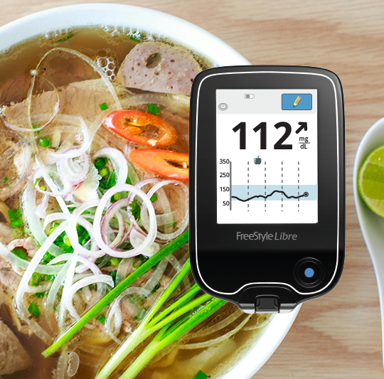  A healthy plate of pasta and marinara sauce. Above the plate is a phone showing a glucose spike on the FreeStyle Libre app.
