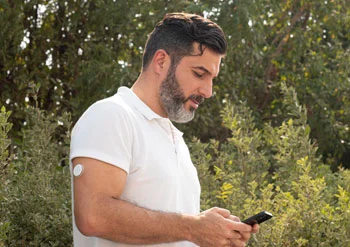 A man applying his FreeStyle Libre sensor on the upper back of his left arm.