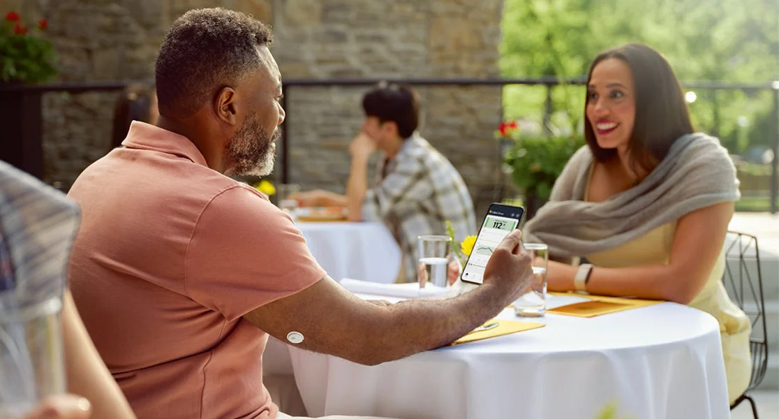 Woman eating with a friend while wearing a FreeStyle Libre 3 Plus sensor