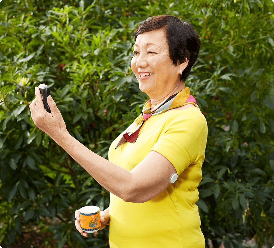 A man wearing a FreeStyle Libre sensor looking at his app next to an inset image of the smartphone app screen.