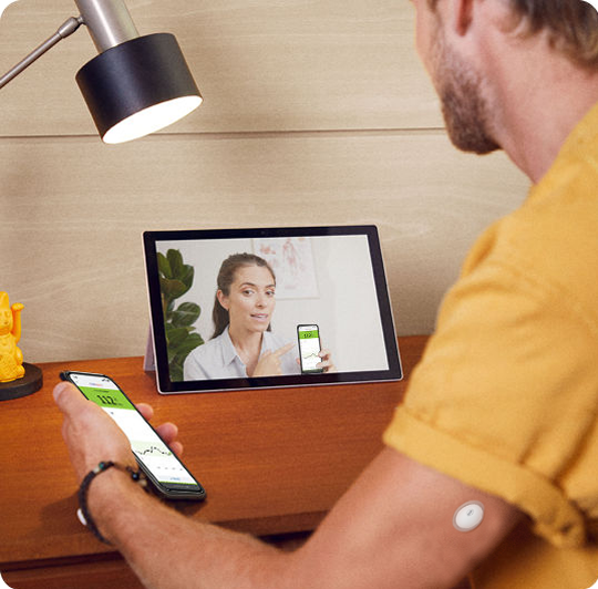 A man wearing a FreeStyle Libre sensor while speaking with his doctor on a tablet.