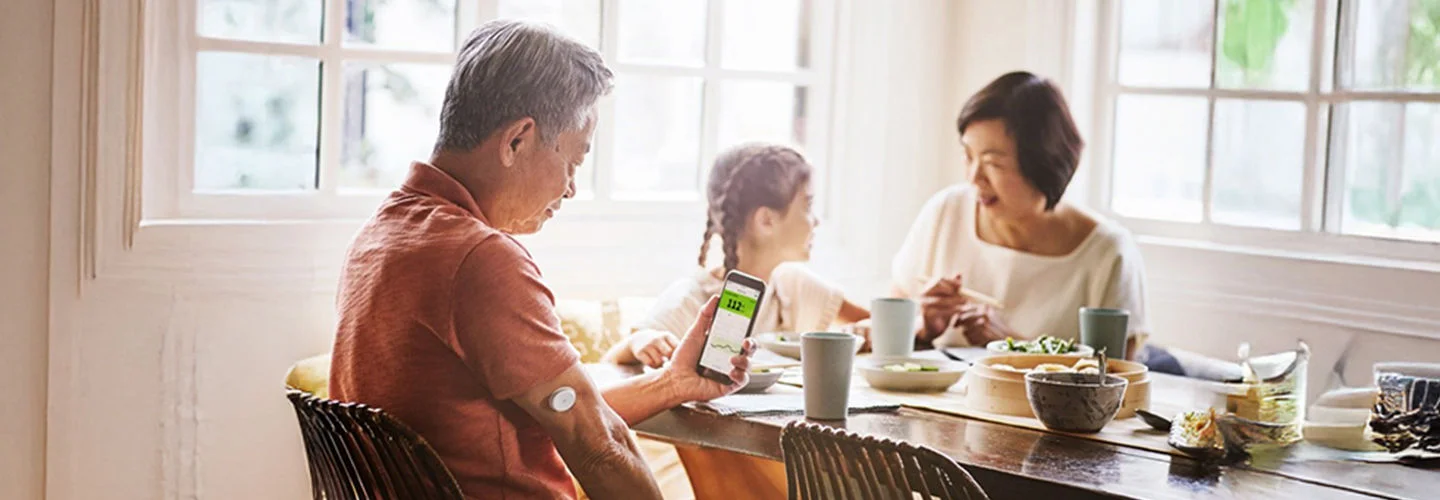 Família sentada na mesa lendo os níveis de glicose