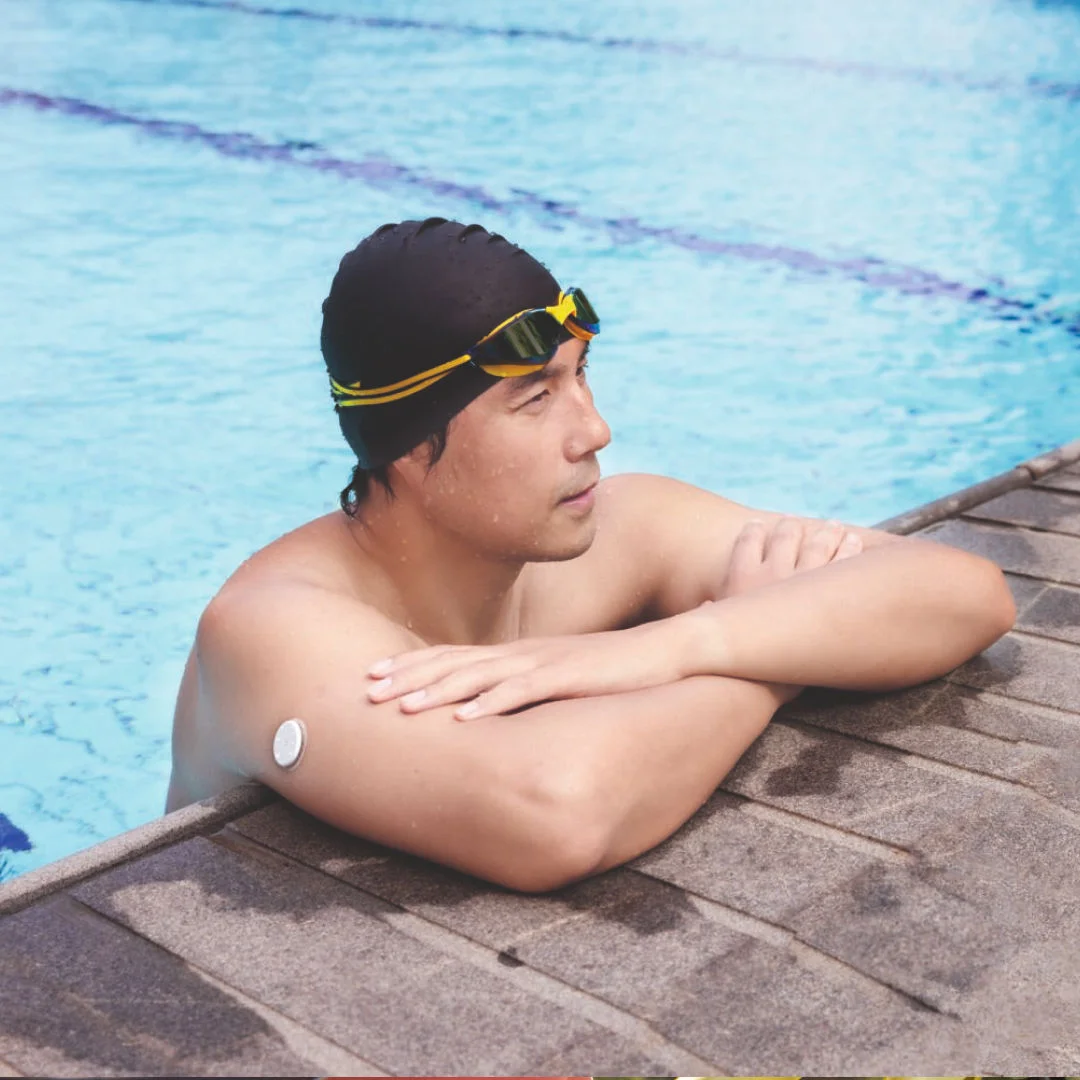 A man swimming with with a FreeStyle Libre sensor visible on the his upper arm.